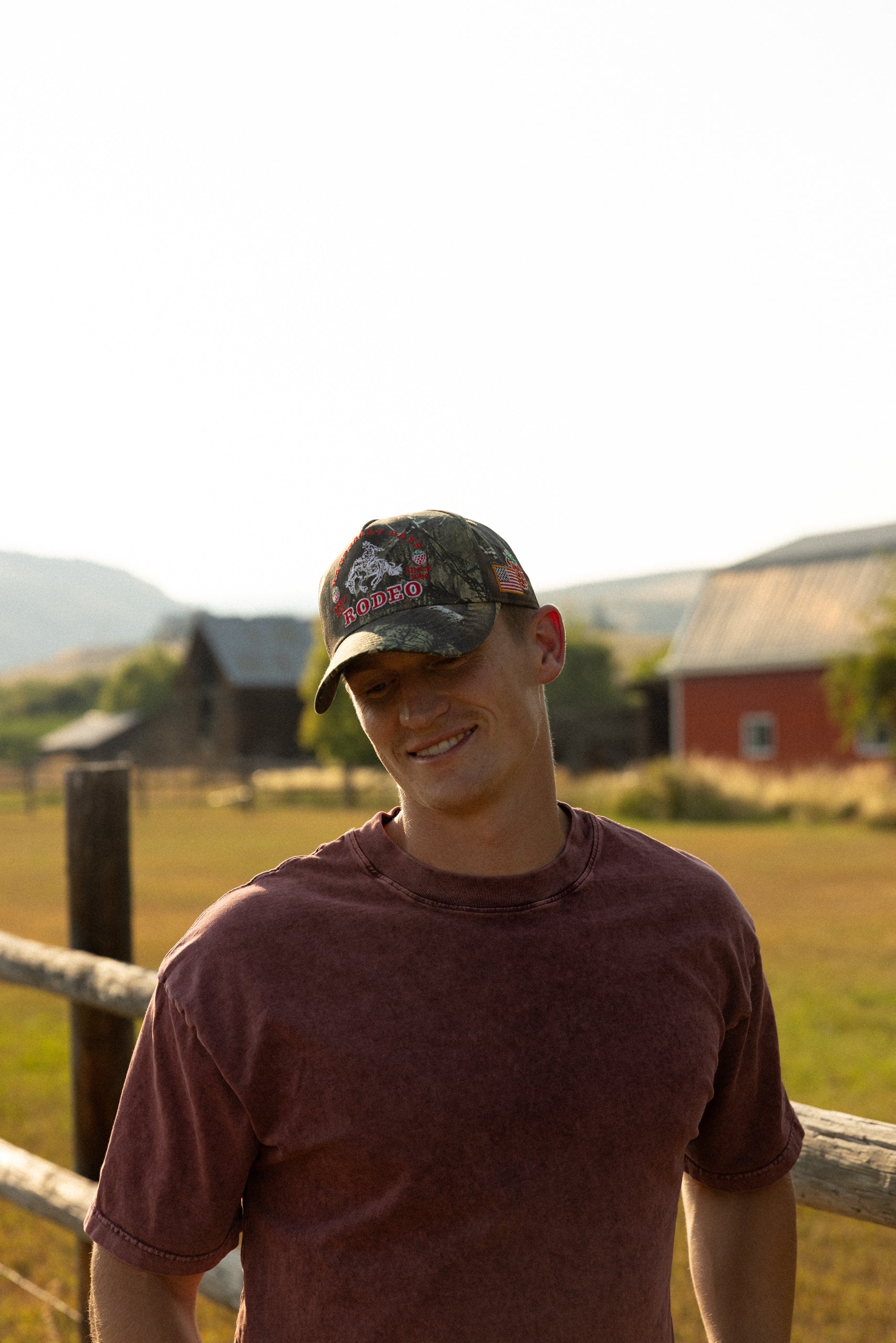 Man in a camo Loud Face cap outside a barn