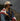 Person wrapped in an American flag with a raspberry days cap, standing outdoors against a dark sky.