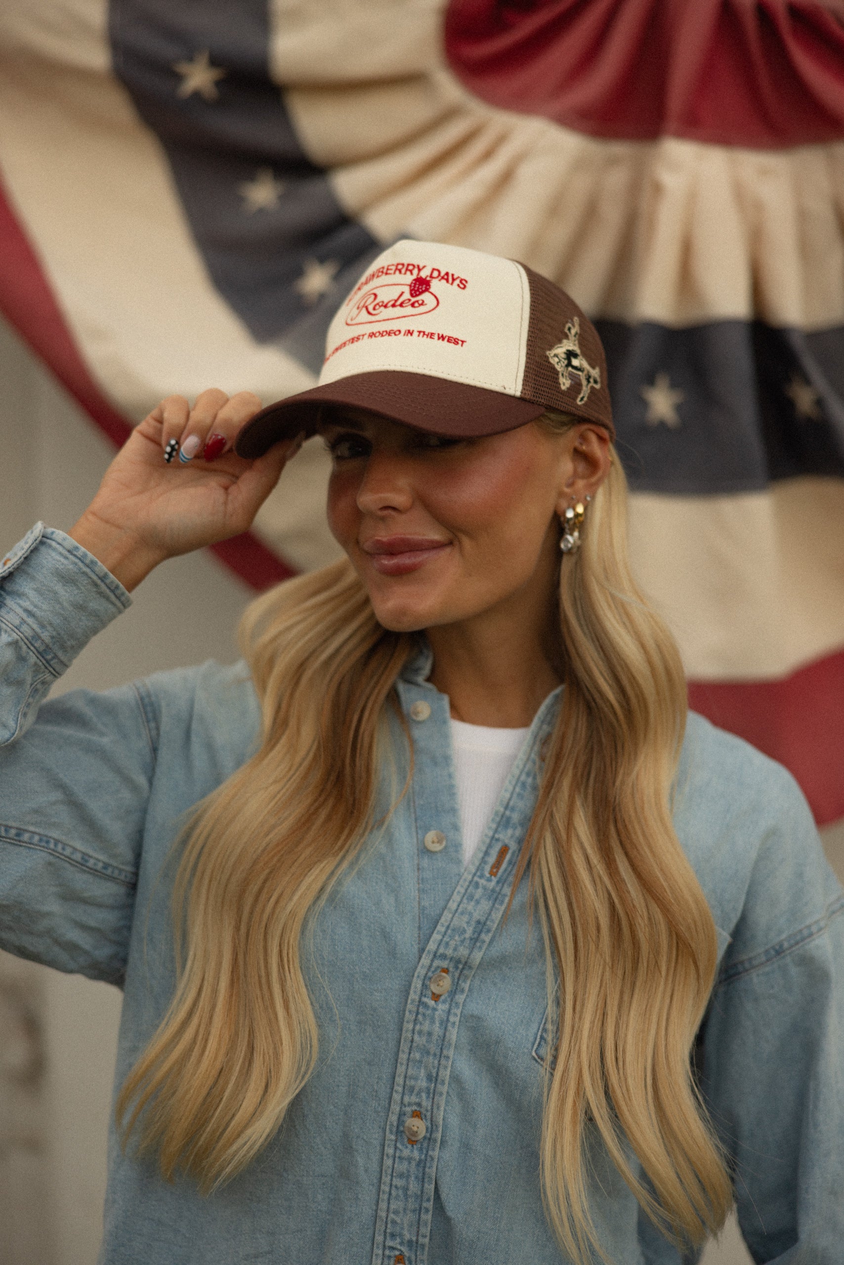 Woman in a denim jacket and Loud Face bronco cap