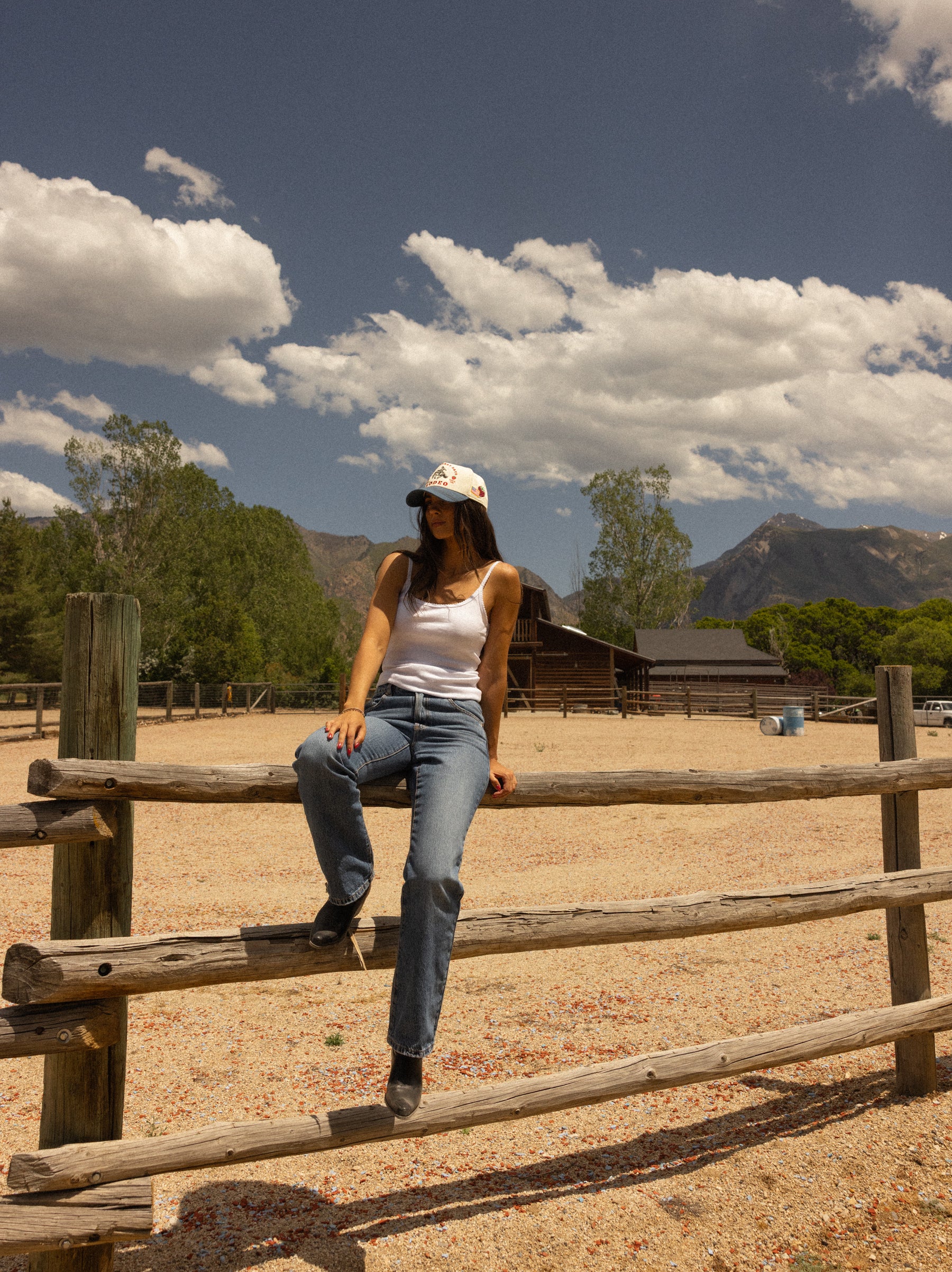 Woman walking beside a corral fence with mountains behind her